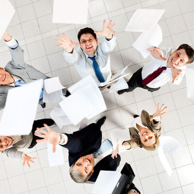 Above view of several successful partners throwing papers in joy